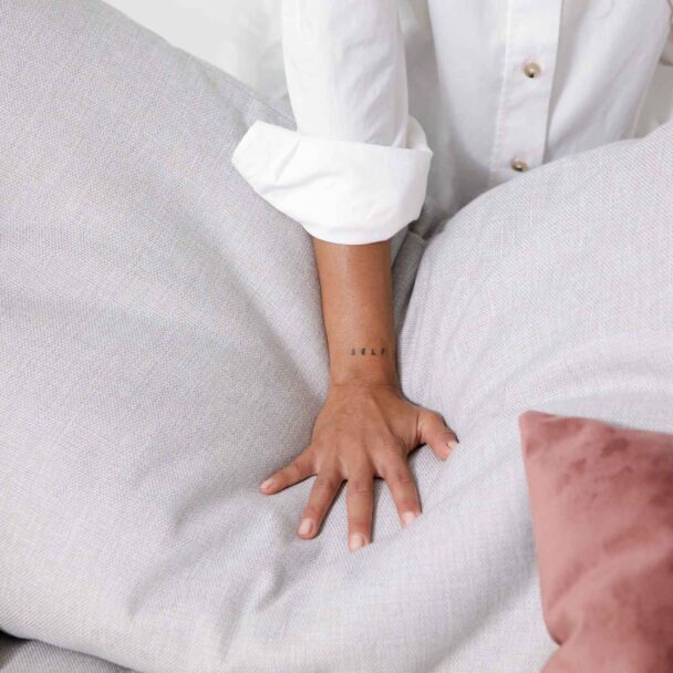 Gros plan d'une main de femme appuyant sur le coussin d'assise moelleux d'un canapé.