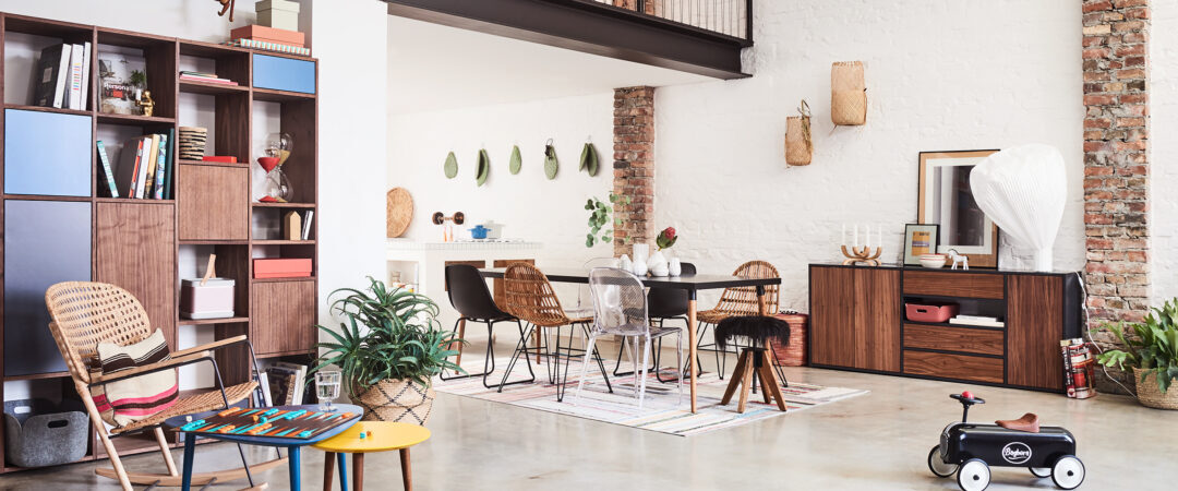 Un salon à la décoration bphème avec un ensemble de chaises dépareillées et des matériaux naturels.
