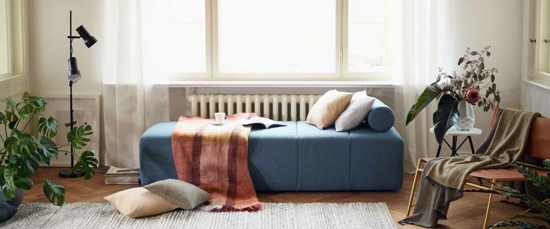Un daybed bleu décoré avec des coussins et un plaid.