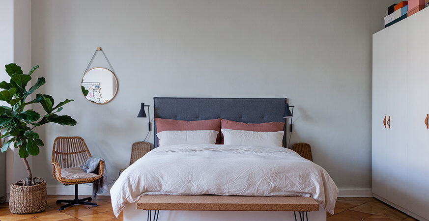 Une chambre décorée avec une tête de lit bleu foncé et du linge de lit blanc et terracotta.