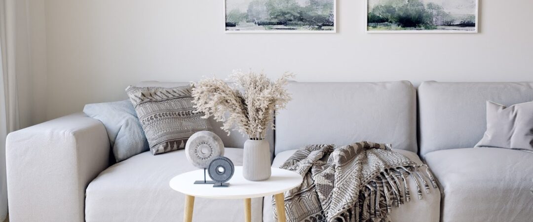 Un salon à la déco cocooning avec un large canapé gris , un plaid et une petite table basse.