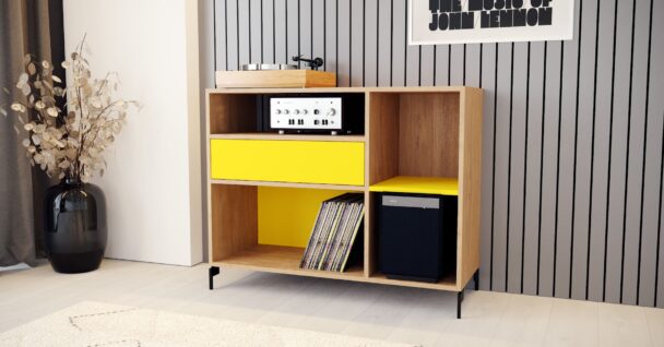 Un meuble de rangement pour vyniles compact composé de compariments ouverts et d'un tiroir jaune.