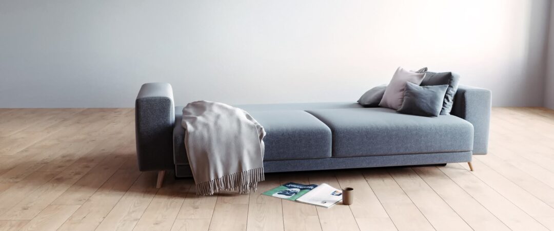 Ein graues Schlafsofa, das in Schlafposition ausgeklappt ist.