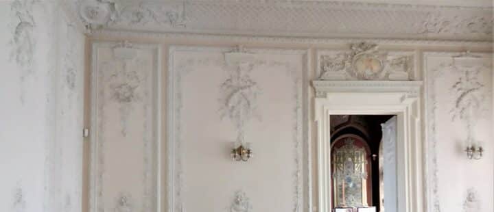 Ein Raum mit Wänden, die mit Zierleisten im Rokoko-Stil verziert sind.