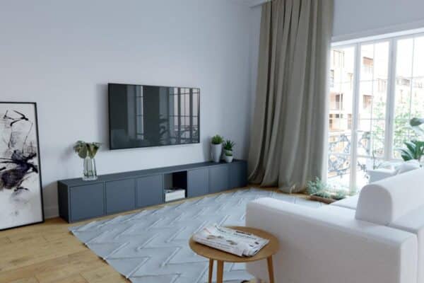Eine TV-Ecke, die mit einem schwarzen TV-Möbel, einem an der Wand hängenden Fernseher und einem weißen Sofa eingerichtet ist.
