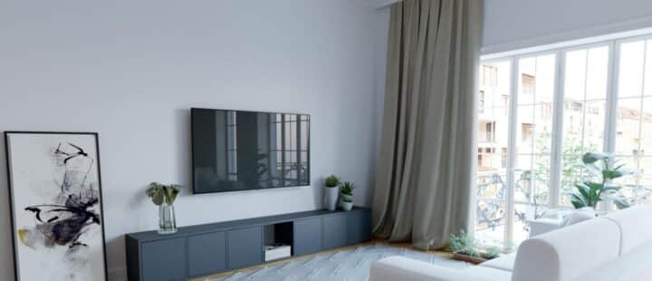 Eine TV-Ecke, die mit einem schwarzen TV-Möbel, einem an der Wand hängenden Fernseher und einem weißen Sofa eingerichtet ist.