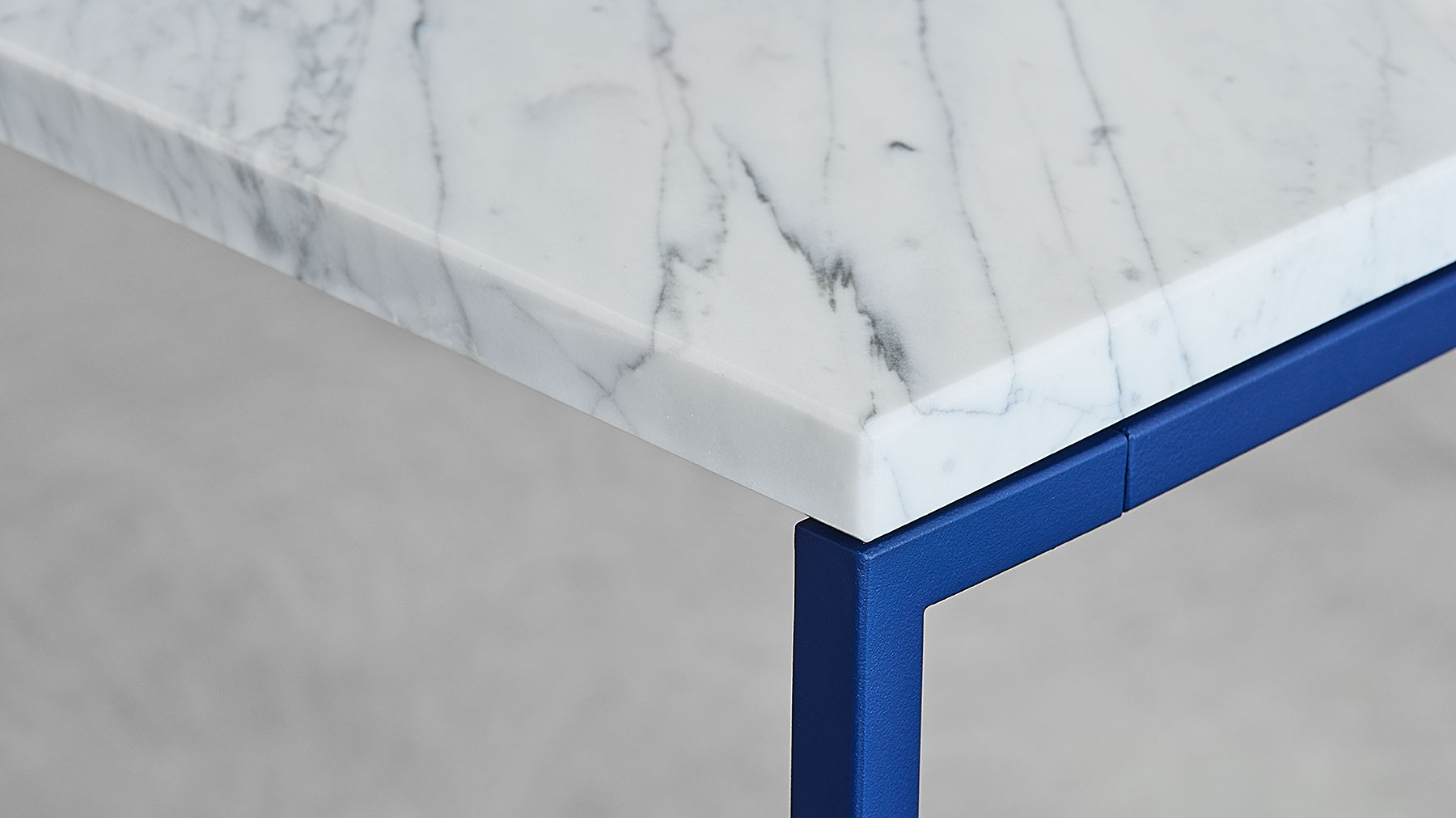 Detail des SYDE Tisch Designs mit weißem Carrara-Marmor und blauem Gestell