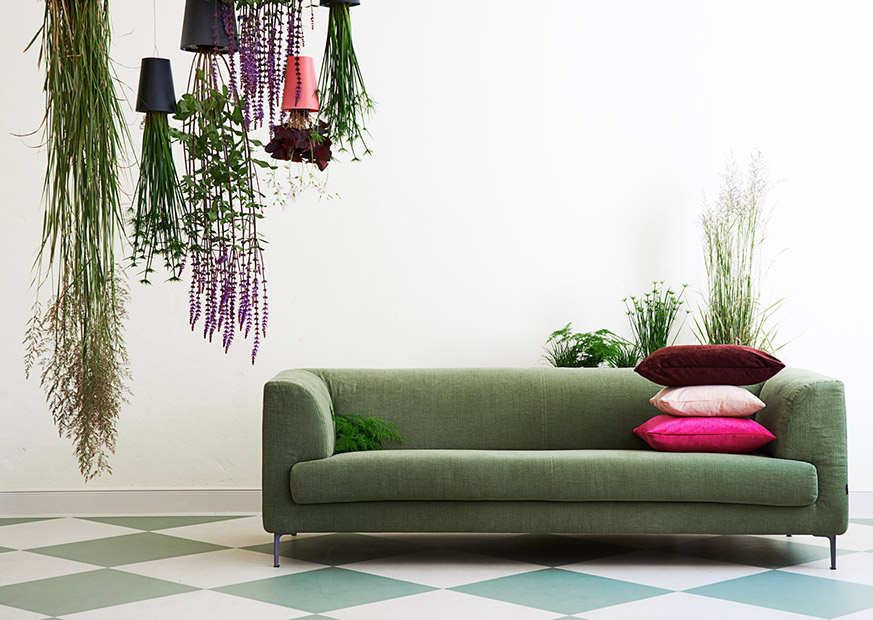 Grünes Sofa geschmückt mit vielen Pflanzen